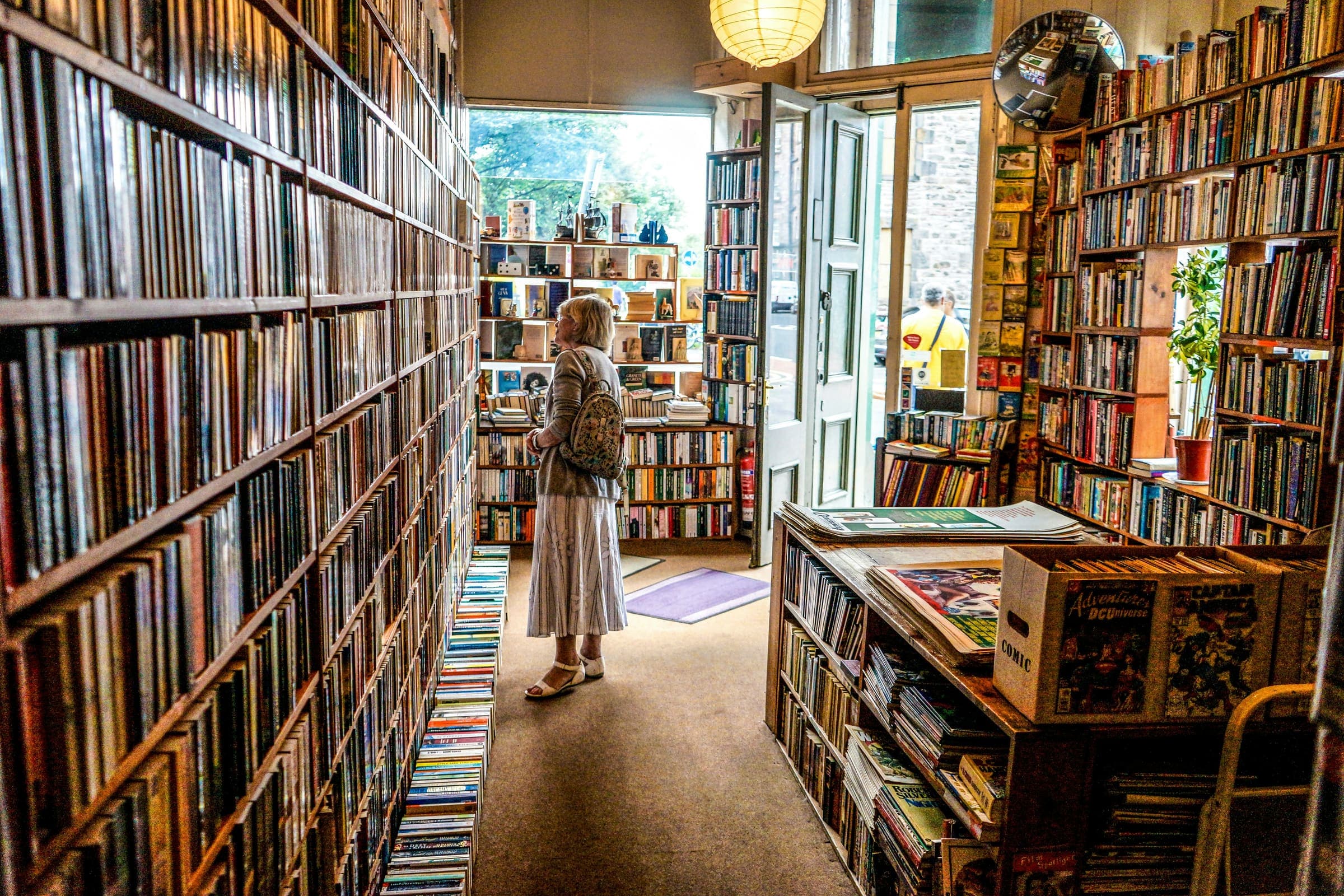 天井まで本が詰まった通路に一人が立って棚を見ている、ある書店の店内。洋書の古本屋で、うちの店内ではありません。